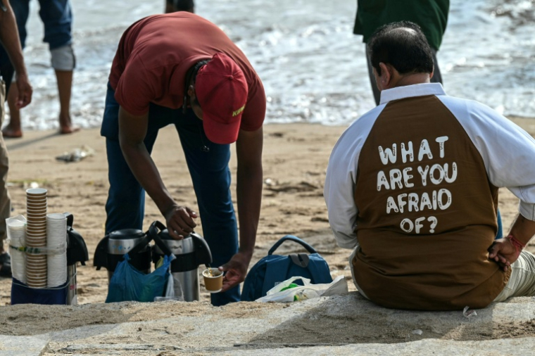 Un vendeur de thé prépare une tasse pour un client sur la plage de Juhu, à Bombay, le 6 août 2026 en Inde ( AFP / Indranil MUKHERJEE )