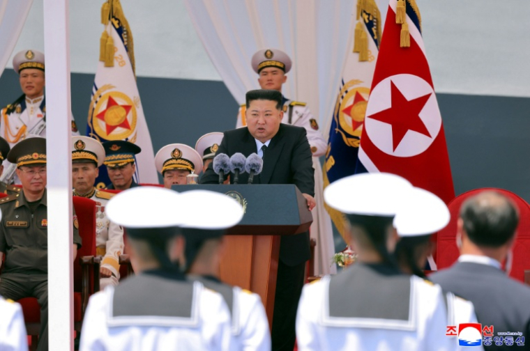 Cette photo, prise le 23 juin 2026 et diffusée le lendemain par l'agence de presse officielle nord-coréenne KCNA, montre le dirigeant nord-coréen Kim Jong Un (au centre) prononçant un discours, au port de Nampo, en Corée du Nord ( KCNA VIA KNS / STR )