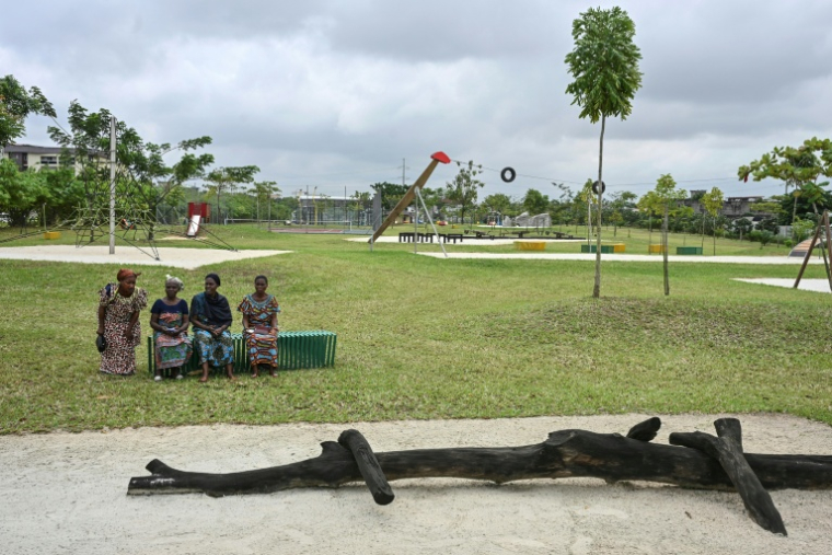 Des visiteurs sont assis, le 1er août 2025, sur un banc du parc urbain d'Akouédo, à Abidjan, construit sur le site d'une ancienne décharge ( AFP / Issouf SANOGO )