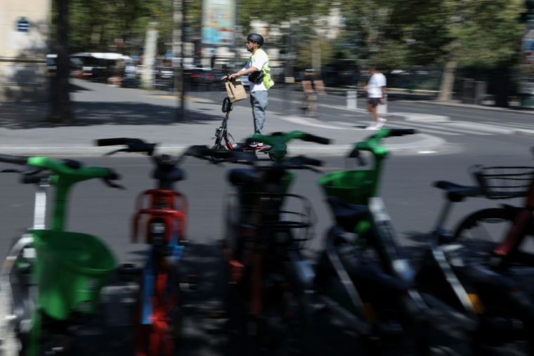 Un homme roule en trottinette électrique dans une rue de Paris, le 11 août 2026 ( AFP / Kenzo TRIBOUILLARD )