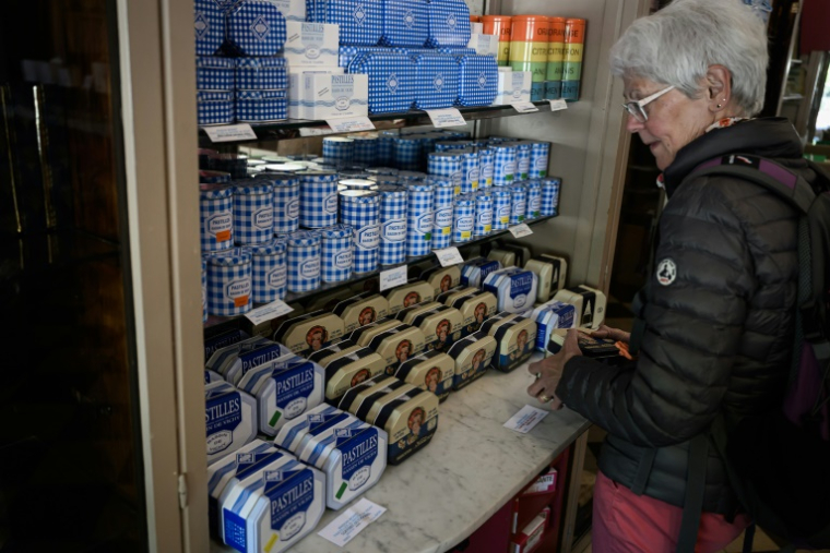 Une cliente regarde les boîtes de pastilles à la menthe Vichy produits par la confiserie Maison Moinet dans une boutique à Vichy, le 13 mai 2025 dans l'Allier ( AFP / JEAN-PHILIPPE KSIAZEK )