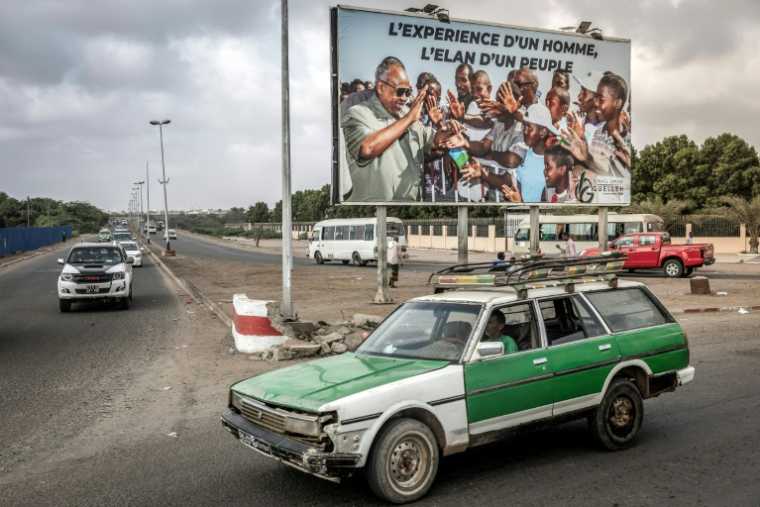 Un taxi passedevant une affiche de campagne du président Ismaïl Omar Guelleh, candidat à sa réélection, le 8 avril 2026 à Djibouti ( AFP / Luis TATO )