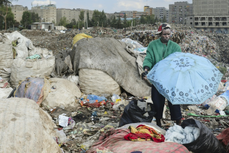 Le créateur de mode Morgan Azedy fouille dans des piles de vêtements mis au rebut dans une décharge à Nairobi, le 6 octobre 2025 au Kenya ( AFP / Tony KARUMBA )