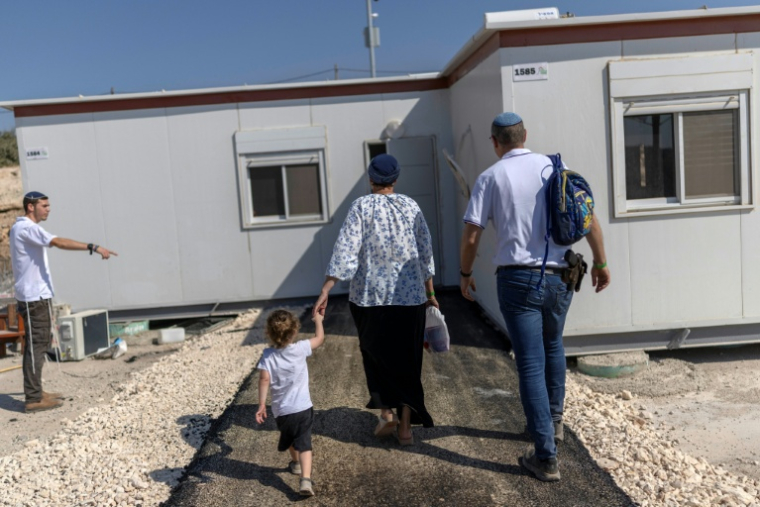 Des colons israéliens devant une maison après la réouverture d'une colonie à Ganim, en Cisjordanie occupée, le 13 août 2026 ( AFP / ilia YEFIMOVICH )