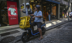 João Paulo Teixeira, 20 ans, livreur de repas, discute avec un collègue alors qu’il s’apprête à livrer une commande dans le centre-ville de Rio de Janeiro, au Brésil, le 17 avril 2026. ( AFP / Mauro PIMENTEL )