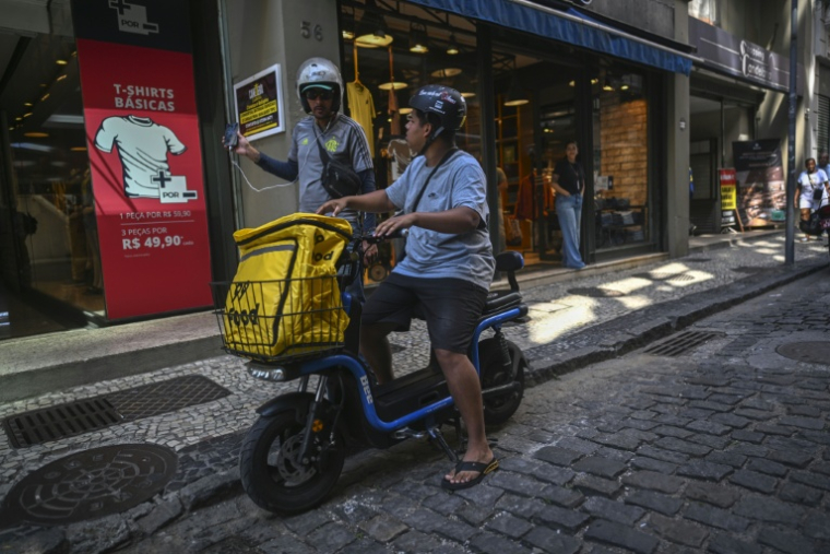 João Paulo Teixeira, 20 ans, livreur de repas, discute avec un collègue alors qu’il s’apprête à livrer une commande dans le centre-ville de Rio de Janeiro, au Brésil, le 17 avril 2026. ( AFP / Mauro PIMENTEL )