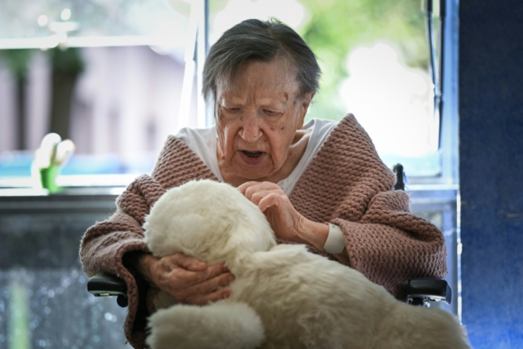 Une patiente de l'hôpital Broca à Paris tient dans ses bras Paro, une peluche phoque animée par IA, le 16 septembre 2026 ( AFP / Lou BENOIST )