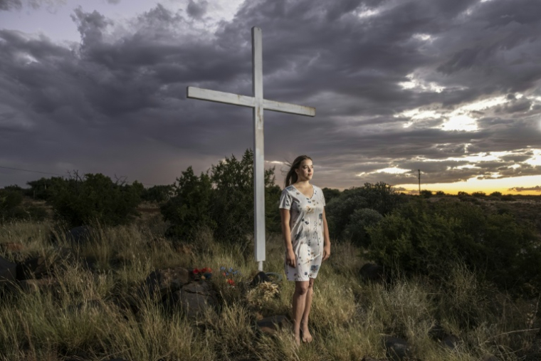 Doret Le Cornu, 23 ans et ayant emménagé il y a trois ans à Orania pose devant une croix dans cette enclave afrikaner de la province du Cap septentrional en Afrique du Sud, le 29 janvier 2026. ( AFP / CAMILLA RICHETTI )