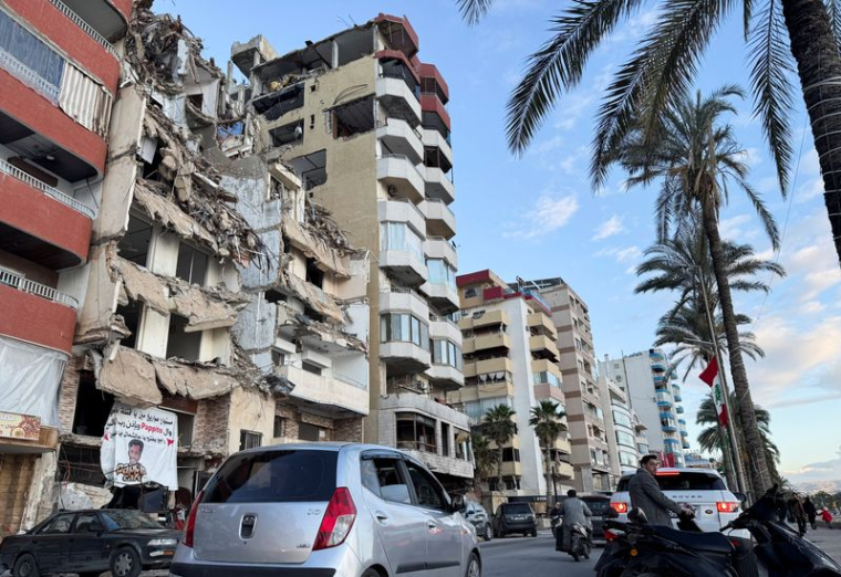 Des voitures passent devant un bâtiment endommagé près de la Corniche, à Tyr