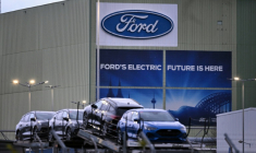 Des voitures du constructeur automobile américain Ford sont alignées sur un camion transporteur devant le logo de l'entreprise à l'usine Ford de Cologne, dans l'ouest de l'Allemagne, le 25 novembre 2024 ( AFP / Ina FASSBENDER )