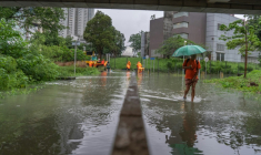 Des personnes marchent dans la rue pendant des pluies torrentielles à Hong Kong, le 5 août 2025 ( AFP / Yan ZHAO )
