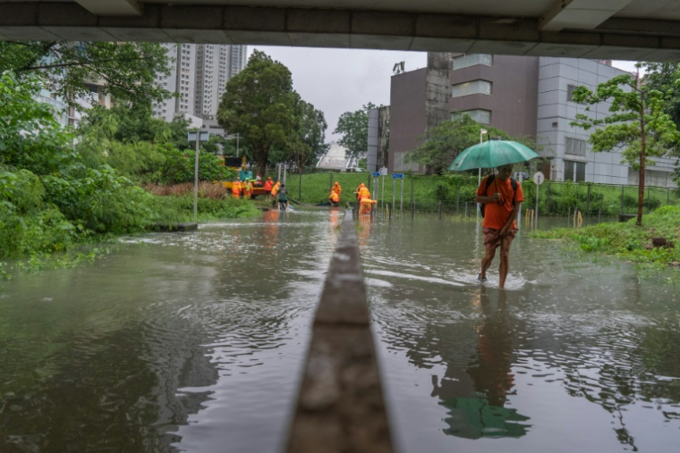 Des personnes marchent dans la rue pendant des pluies torrentielles à Hong Kong, le 5 août 2025 ( AFP / Yan ZHAO )