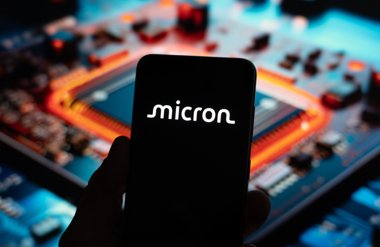 Un écran de smartphone avec le logo de Micron Technology sur fond de circuit imprimé. (Crédits: Adobe Stock)