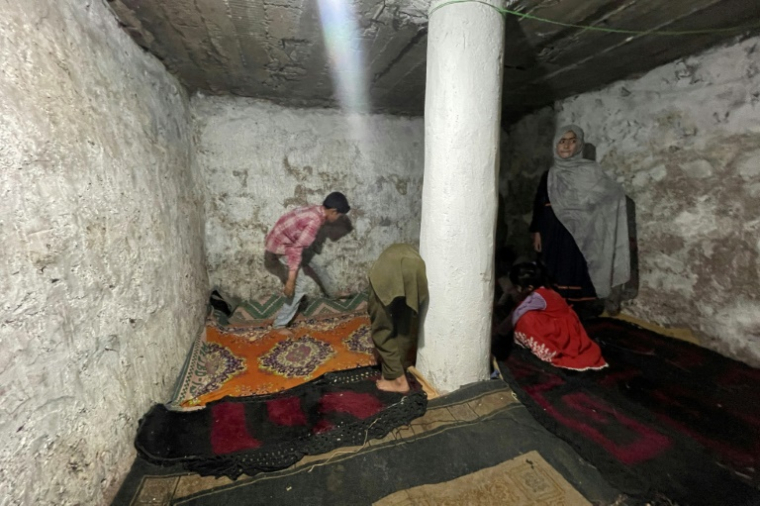 Une famille installe des tapis à l'intérieur d'un bunker souterrain dans le village de Chakothi, au Cachemire sous administration pakistanaise, près de la ligne de contrôle (LoC), le 27 avril 2025 ( AFP / Sajjad QAYYUM )