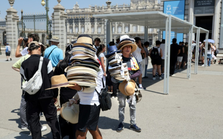 Des vendeurs de chapeaux devant le Palais royal à Madrid en pleine canicule, le 2 juillet 2025 ( AFP / Thomas COEX )