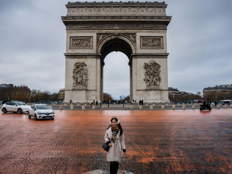 La place de l'Etoile à Paris a pris le 12 décembre 2025 une couleur orangée après avoir été aspergée de  peinture par des militants écologistes dénonçant le peu d'avancées, 10 ans après l'Accord de Paris sur le climat ( AFP / Dimitar DILKOFF )