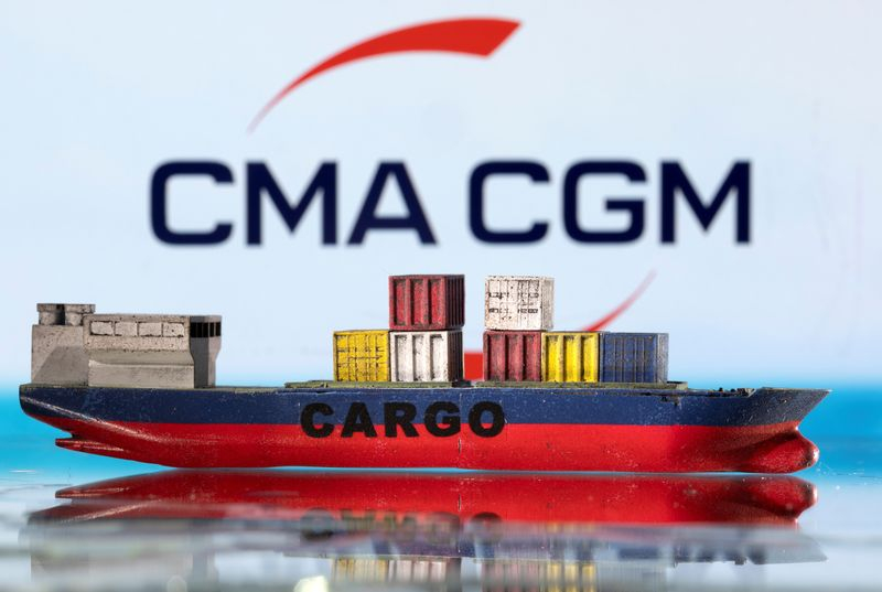 Un modèle de bateau cargo est photographié devant le logo de CMA CGM.
