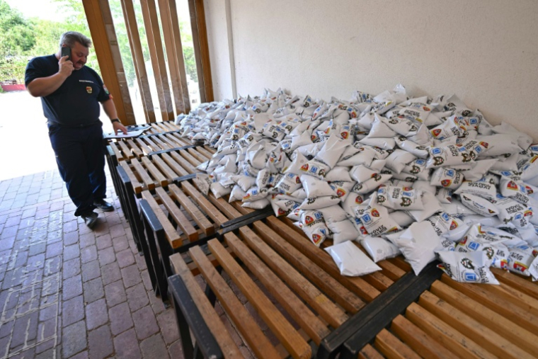 Un responsable municipal prépare des sacs d'eau potable en vue de leur distribution dans le village hongrois de Szada, en pleine vague de chaleur, le 30 juin 2026 ( AFP / Attila KISBENEDEK )