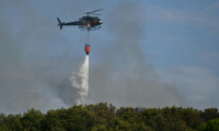 Un hélicoptère Airbus H125 largue de l'eau sur un incendie de forêt à Saint-Julien Les Martigues, au nord-ouest de Marseille, le 18 juillet 2025 dans les Bouches-du-Rhône ( AFP / Christophe SIMON )
