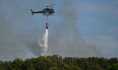 Un hélicoptère Airbus H125 largue de l'eau sur un incendie de forêt à Saint-Julien Les Martigues, au nord-ouest de Marseille, le 18 juillet 2025 dans les Bouches-du-Rhône ( AFP / Christophe SIMON )