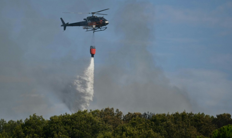 Un hélicoptère Airbus H125 largue de l'eau sur un incendie de forêt à Saint-Julien Les Martigues, au nord-ouest de Marseille, le 18 juillet 2025 dans les Bouches-du-Rhône ( AFP / Christophe SIMON )