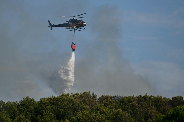 Un hélicoptère Airbus H125 largue de l'eau sur un incendie de forêt à Saint-Julien Les Martigues, au nord-ouest de Marseille, le 18 juillet 2025 dans les Bouches-du-Rhône ( AFP / Christophe SIMON )