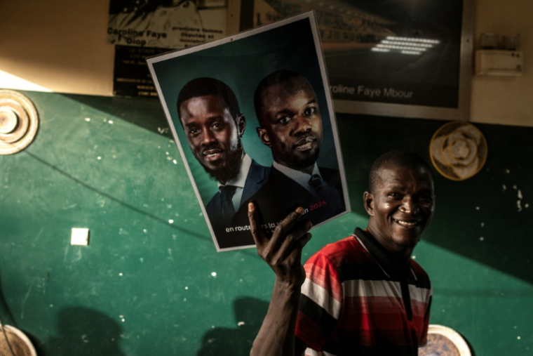 Un partisan du candidat à la présidentielle Bassirou Diomaye Faye et du leader de l'opposition Ousmane Sonko brandit une affiche pendant la campagne présidentielle à Mbour (Sénégal), le 22 mars 2024 ( AFP / JOHN WESSELS )