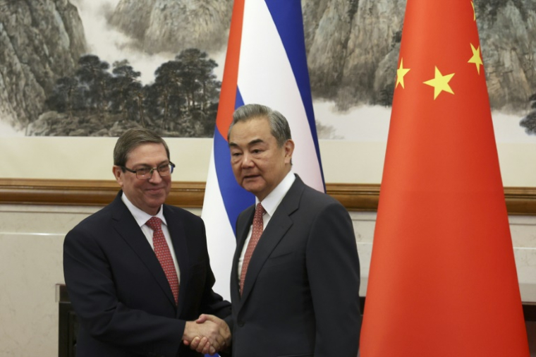 Le ministre chinois des Affaires étrangères Wang Yi (d) et le ministre cubain des Affaires étrangères Bruno Rodriguez Parrilla se serrent la main avant leur rencontre à la maison d'hôtes d'Etat Diaoyutai à Pékin, le 12 mai 2025 ( POOL / FLORENCE LO )