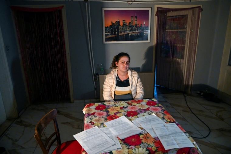 Zsuzsanna Marton, mère de trois enfants, assise à sa table où sont étalées des lettres officielles, le 25 septembre 2025 à Szentistvan, dans le nord-est de la Hongrie ( AFP / Attila KISBENEDEK )