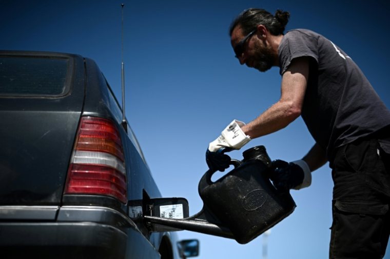Un membre de "Roule ma frite", une association spécialisée dans la récupération et le recyclage des huiles de friture usagées en circuit court, remplit le réservoir d'une voiture diesel avec de l'huile usagée recyclée, le 10 mai 2022 à Bourcefranc-le-Chapus, en Charente-Maritime ( AFP / Philippe LOPEZ )