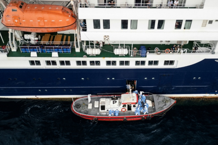 Vue aérienne montrant du personnel de santé aidant des personnes à monter à bord d’un bateau depuis le navire de croisière MV Hondius, à l’arrêt au large du port de Praia, la capitale du Cap-Vert, le 6 mai 2026 ( AFP / - )