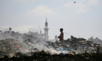 Un garçon palestinien cherche des objets à sauver dans une décharge d'ordures à Al-Bureij, dans le centre de la bande de Gaza, le 7 juillet 2025 ( AFP / Eyad BABA )