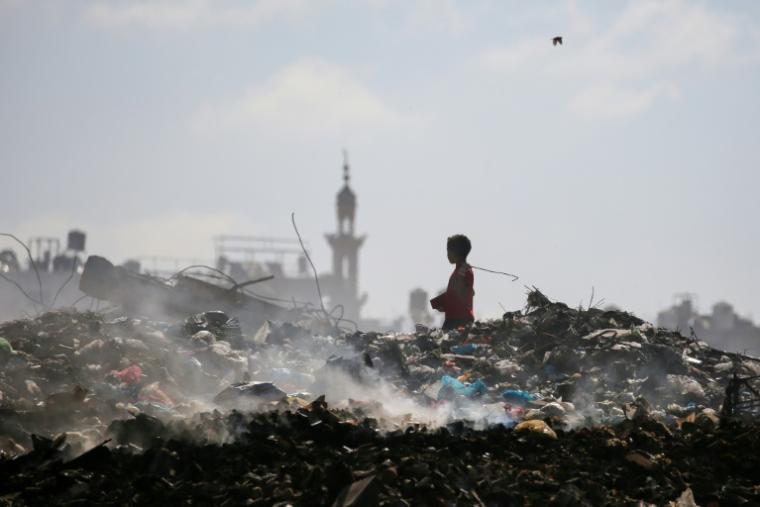 Un garçon palestinien cherche des objets à sauver dans une décharge d'ordures à Al-Bureij, dans le centre de la bande de Gaza, le 7 juillet 2025 ( AFP / Eyad BABA )