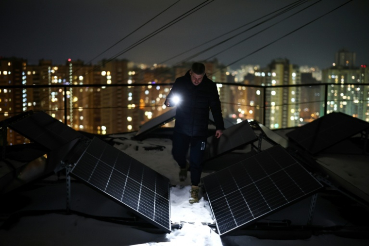 Un homme inspecte des panneaux solaires, le 22 février 2026, à Kiev, à la suite de coupures d'électricité ( AFP / HENRY NICHOLLS )
