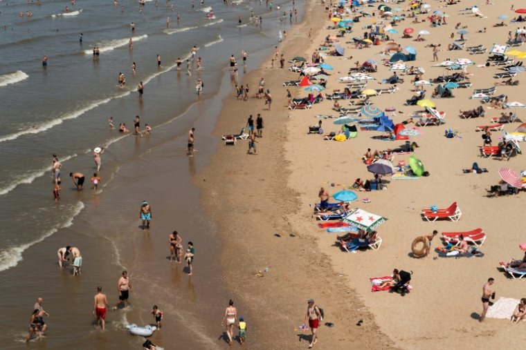 Des personnes se rafraîchissent au bord de la mer sur la plage de Zuiderstrand, à La Haye, aux Pays-Bas, le 26 juin 2026, alors que le service météorologique néerlandais (KNMI) a émis une alerte rouge pour chaleur extrême dans toutes les provinces ( AFP / Lina SELG )