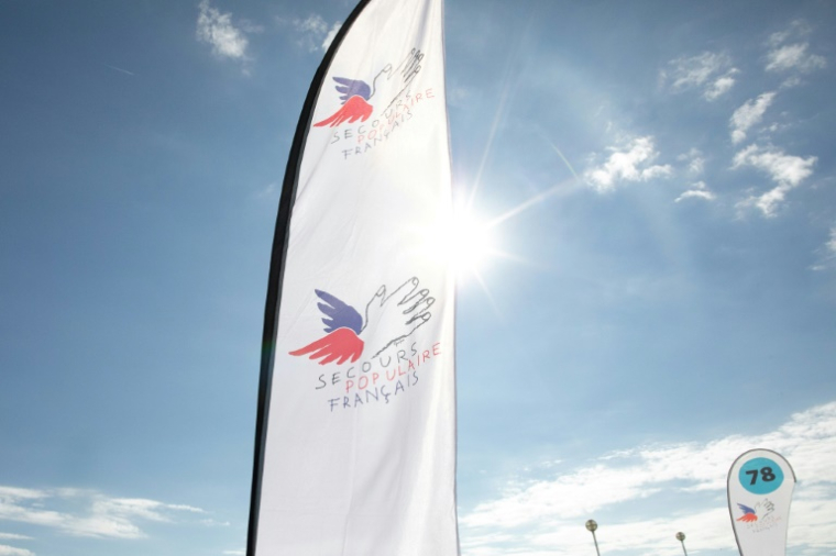 Le logo du Secours Populaire  lors de la campagne "Journées des oubliés des vacances", le 24 août 2022 à Deauville ( AFP / Lou BENOIST )