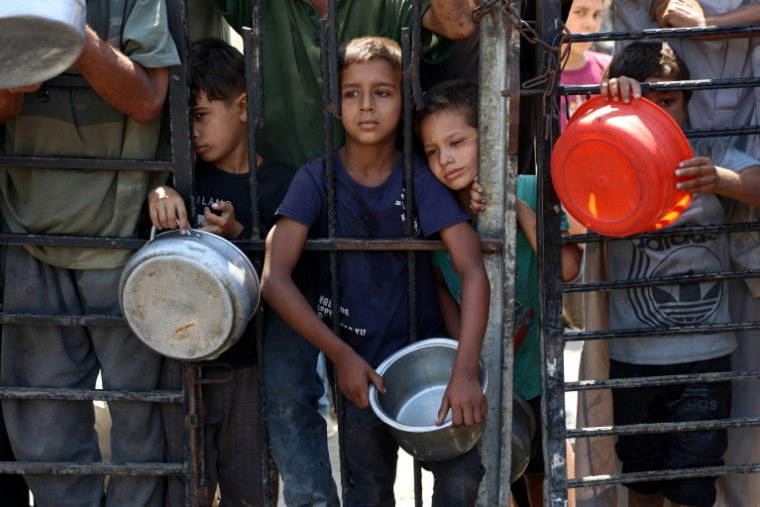 Des enfants palestiniens attendent de recevoir de la nourriture devant une organisation de charité locale distribuant du riz cuit, dans la ville de Gaza, le 23 août 2025 ( AFP / Omar AL-QATTAA )
