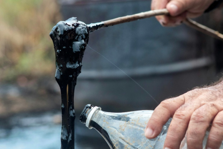 Héctor Valero Balestrini prélève un échantillon de résidus de pétrole brut qui ont affleuré au Cerro Miosa, à Mene Grande, dans l’État de Zulia, au Venezuela. ( AFP / Margioni BERMÚDEZ )