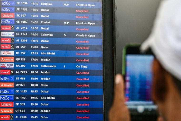 Un passager prend une photo d'un tableau d'affichage des vols annulés vers les destinations du Moyen-Orient à l'aéroport international de Bombay le 1er mars 2026 en Inde ( AFP / Punit PARANJPE )