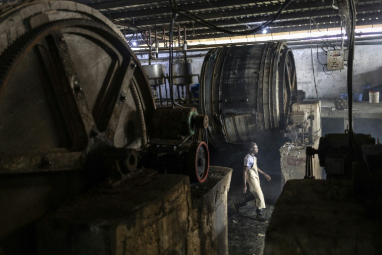 Un ouvrier d'usine marche entre des fûts à l'usine Z-Tannery de Kano, le 11 septembre 2025. Kano, centre historique du cuir, approvisionne des géants du luxe tels que Louis Vuitton, Gucci et Ralph Lauren, le Nigeria exportant près de 90 % de ses peaux à l'étranger. Mais comme la finition est effectuée en Europe, le label "Made in Nigeria" disparaît, remplacé par "Made in Italy" ou "Made in Spain". Aujourd'hui, certains créateurs nigérians tentent de redonner ses lettres de noblesse au cuir de leur pays en créant des marques locales.  ( AFP / OLYMPIA DE MAISMONT )