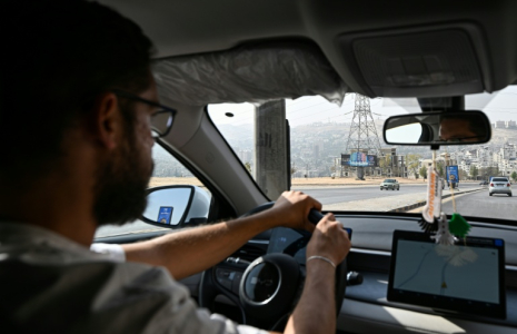 Ahmad al-Lahham, chauffeur pour l'une des principales applications de taxis "Yalla Go", au volant son véhicule hybride rechargeable à Damas, le 25 octobre 2026 en Syrie ( AFP / LOUAI BESHARA )
