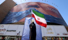 Une Iranienne brandit le drapeau de son pays, devant une panneau représentant le président américain Donald Trump, à Téhéran le 10 mai 2026 ( AFP / ATTA KENARE )