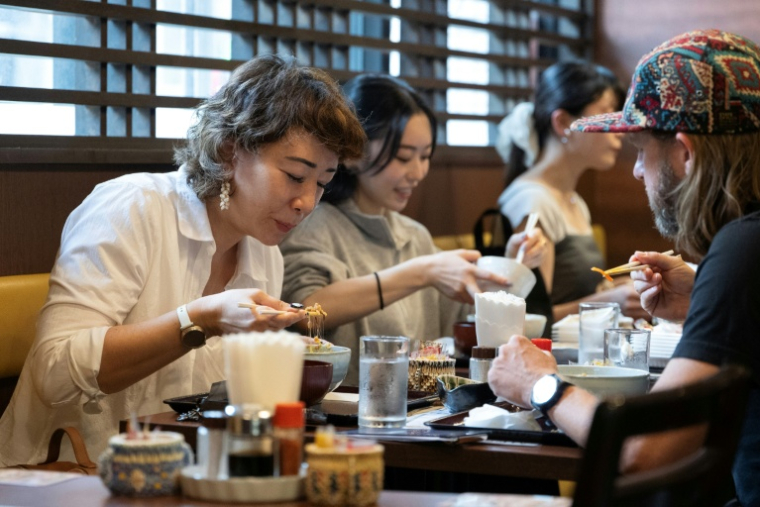 Wesley Smith (D) et son épouse Maya Bourdeau déjeune au restaurant Natto Kobo Sendai-ya à Tokyo le 8 juin 2026  ( AFP / Andrew CABALLERO-REYNOLDS )