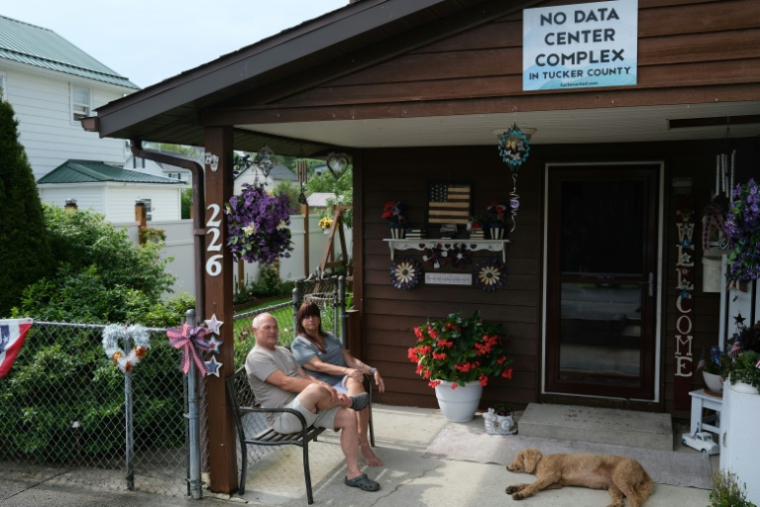 Pat et Jojo Pregley avec leur panneau d'opposition au projet local de data center devant leur maison à Davis, en Virginie-Occidentale, le 30 juin 2025 ( AFP / Ulysse BELLIER )