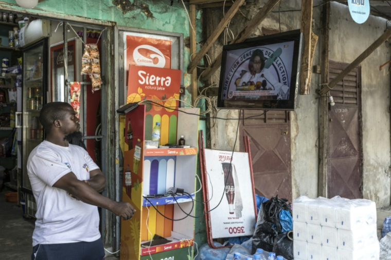 Un Guinéen regarde un écran de télévision diffusant l'annonce des résultats partiels de l'élection présidentielle guinéenne par la directrice générale des élections (DGE), Djenabou Touré, près des bureaux de la DGE à Conakry, le 30 décembre 2025. ( AFP / PATRICK MEINHARDT )
