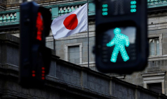 Le drapeau national japonais hissé au sommet du siège de la Banque du Japon est vu entre les feux de signalisation à Tokyo