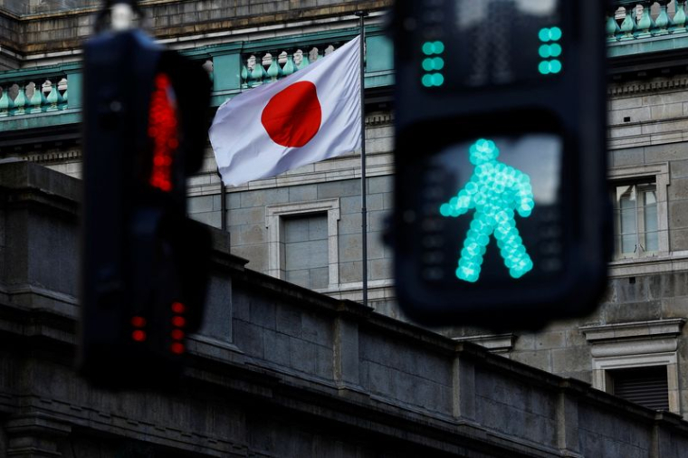 Le drapeau national japonais hissé au sommet du siège de la Banque du Japon est vu entre les feux de signalisation à Tokyo