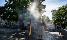 Une femme se rafraîchit à une fontaine brumisatrice à Berlin, le 22 juin 2026 lors d'un épisode de canicule en Europe ( AFP / John MACDOUGALL )