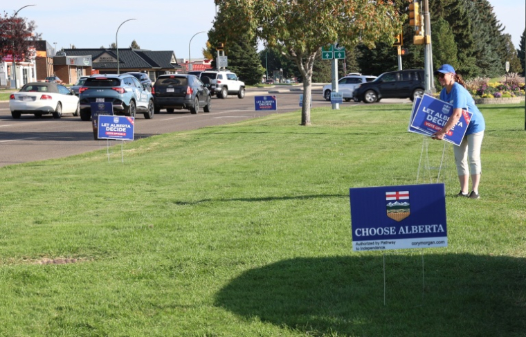 Un militant favorable à la séparation de l'Alberta du Canada plante des affiches "Choose Alberta", le 23 septembre 2026 à Medicine Hat ( AFP / ABED ZAQ )