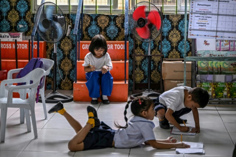Des élèves en pleine activité sous des ventilateurs dans une école primaire sur l'île de Baseco, à Manille, le 21 mars 2025 ( AFP / Jam STA ROSA )